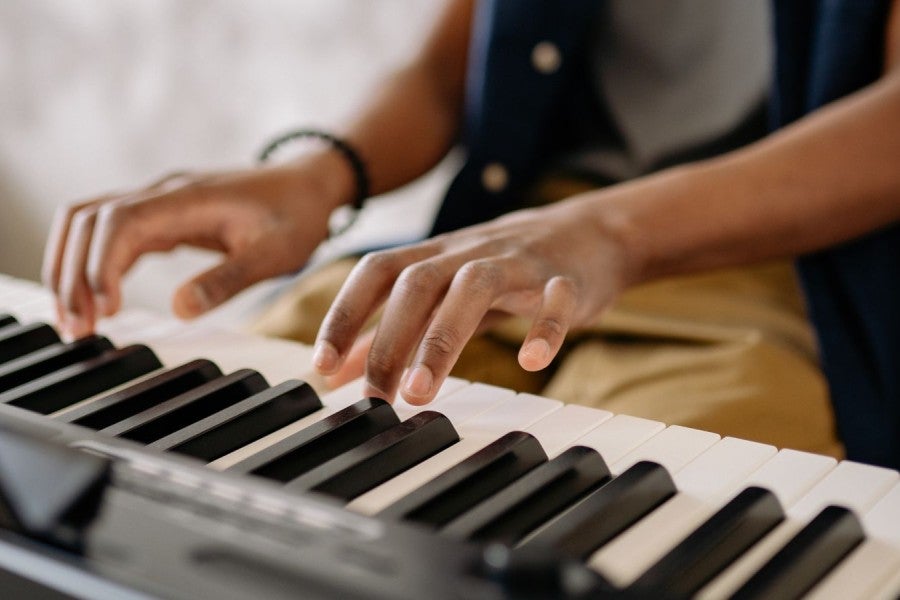 A student is playing at a piano keyboard.